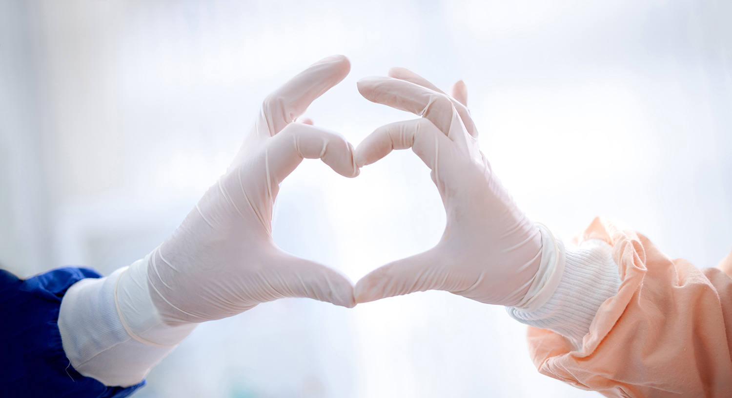 Closeup of cardiovascular surgeons' gloved hands forming a heart shape